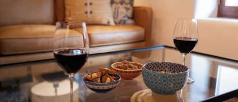 A glass table with two wine glasses, three bowls, and a woven placemat.