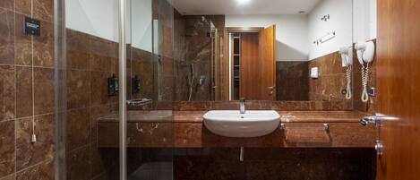 A modern bathroom with a glass-enclosed shower, a sink, and a toilet.
