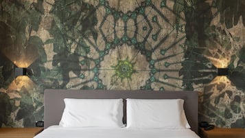 Hotelkamer met een groot bed, een hoofdeinde, twee nachtkastjes en een muur met een ingewikkeld geometrisch patroon.