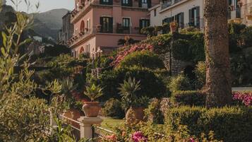 Un quartier résidentiel situé sur une colline, avec des maisons à étages, de beaux jardins et un palmier.