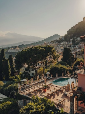 A poolside area with lounge chairs, a pool, and a view of a hillside town. - Grand Hotel Timeo, A Belmond Hotel, Taormina (Taormina)