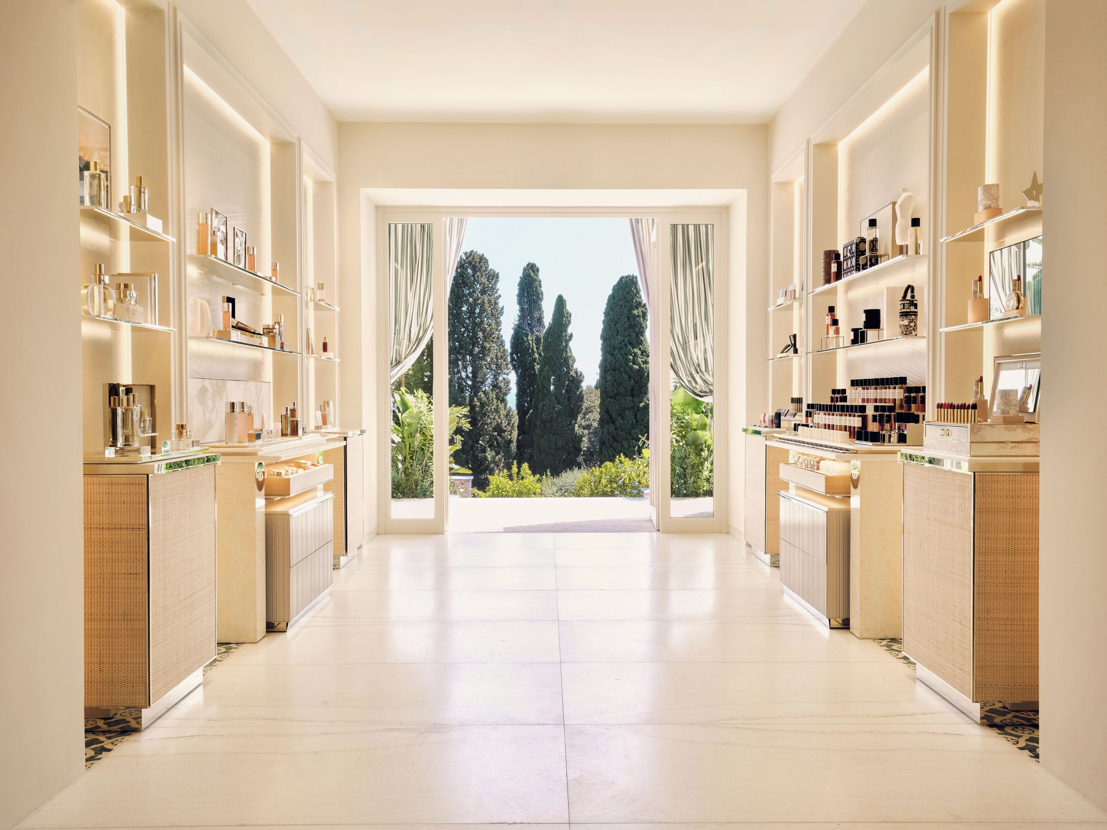 A spacious, well-lit room with a large window, shelves with various items, and a view of tall trees.