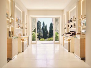 A spacious, well-lit room with a large window, shelves with various items, and a view of tall trees.