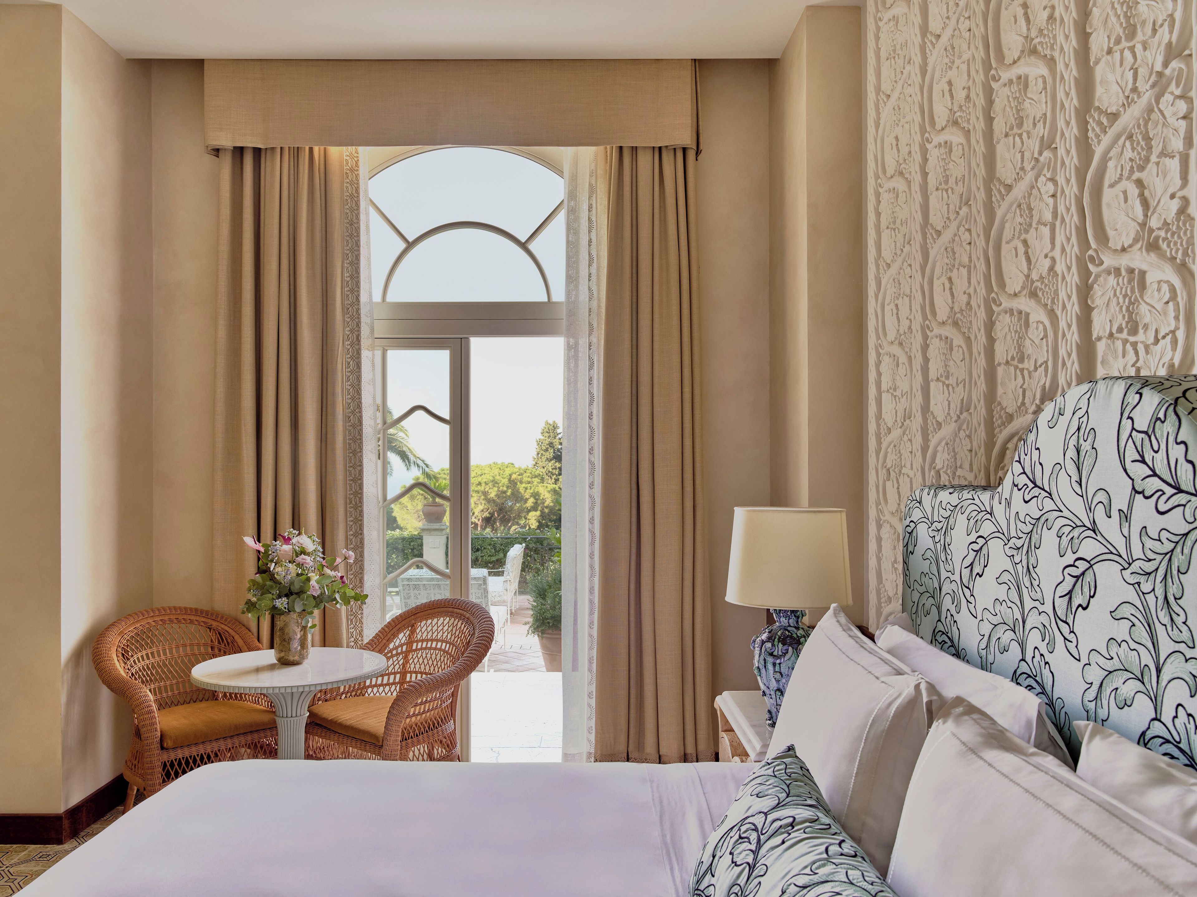 Ein Hotelzimmer mit Bett, Stuhl, Tisch und Blick durch ein Fenster.