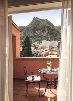 A balcony with a table and chairs, overlooking a mountainous town with buildings. - Grand Hotel Timeo, A Belmond Hotel, Taormina (Taormina)