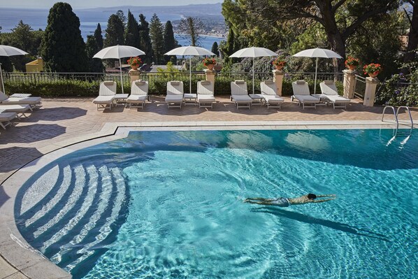 Una piscina al aire libre, sombrillas, tumbonas