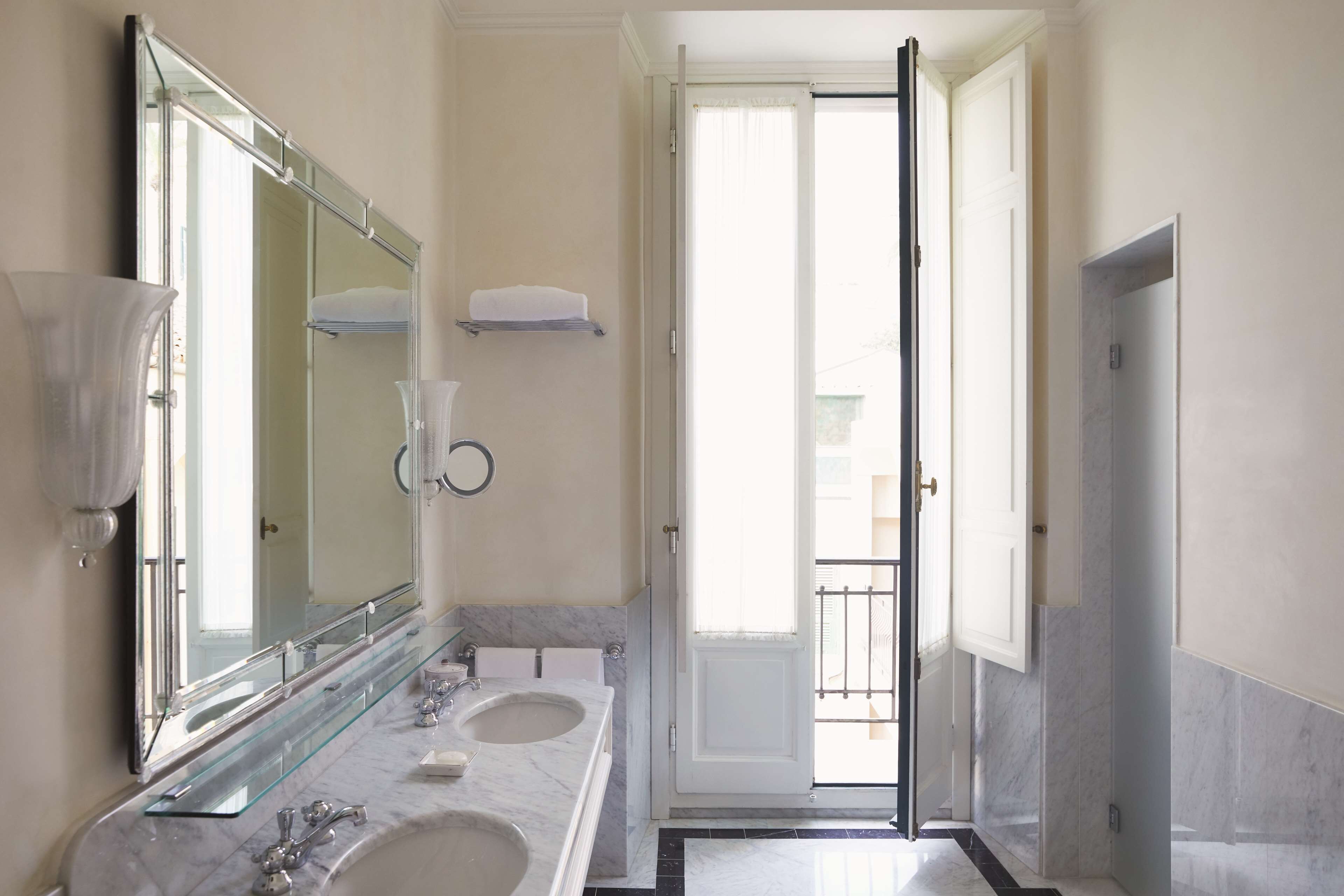A bathroom with two sinks, a large mirror, and a door leading to a balcony.