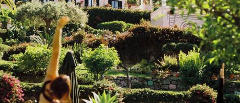 Una persona practicando yoga en un jardín con un edificio al fondo.