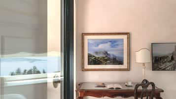 Quarto com escrivaninha, cadeira e duas fotografias emolduradas na parede.