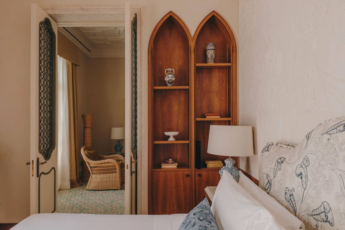 Un dormitorio con una cama, un armario de madera, una silla y una mesita de noche con una lámpara.