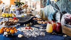 Una mesa de buffet con diversos alimentos y bebidas, sobre un mantel azul estampado.