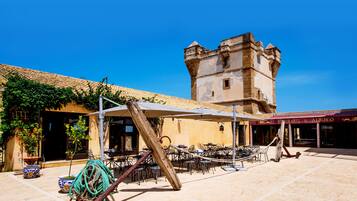 A courtyard with outdoor seating, a tower, and a building with a sign reading "Ristorante & Albergo".