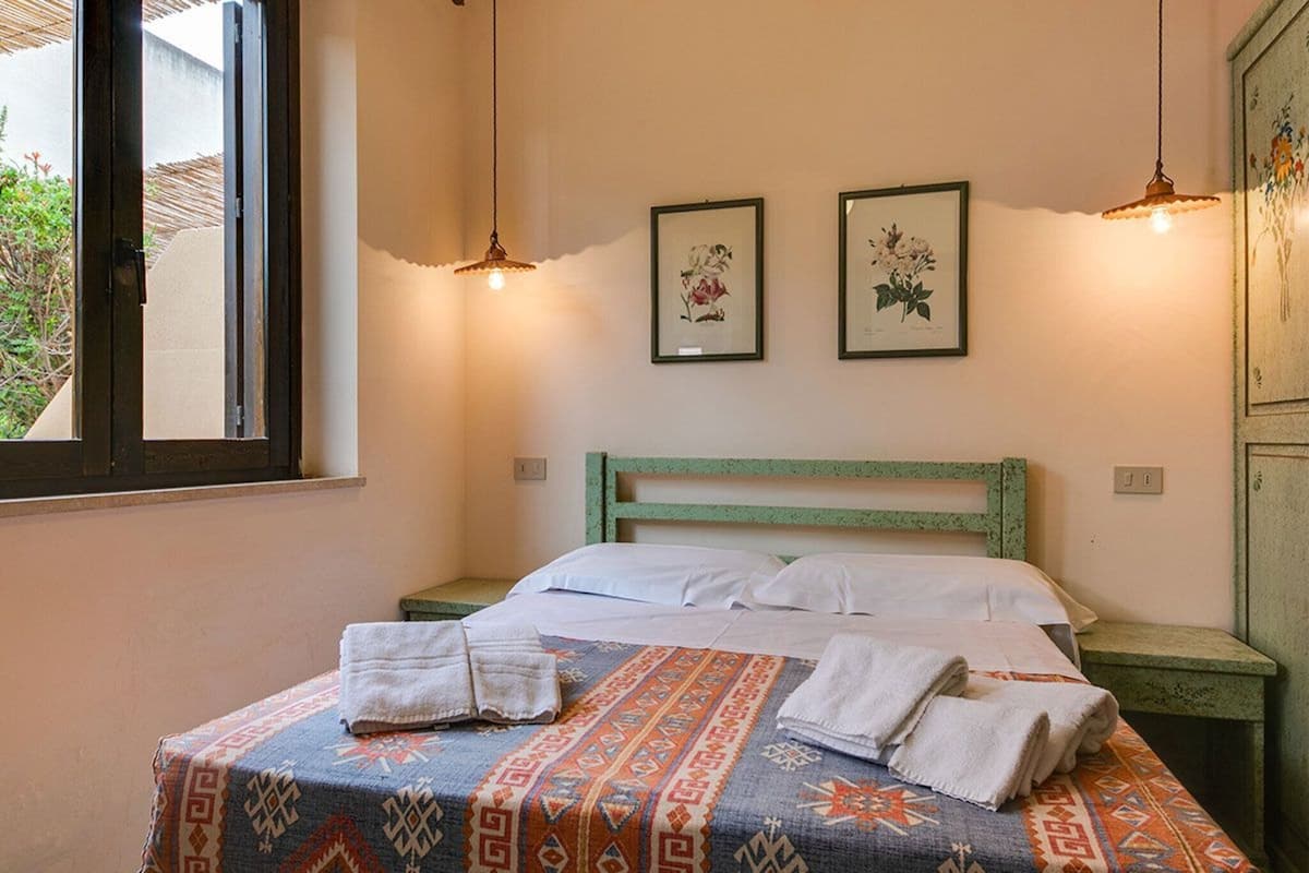 Une chambre à coucher avec un lit, deux tableaux encadrés accrochés au mur et une fenêtre.