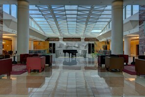 A spacious lobby with a grand piano, red seating, and a high ceiling with skylights. - VIP Executive Entrecampos Hotel & Conference (Lisbon)