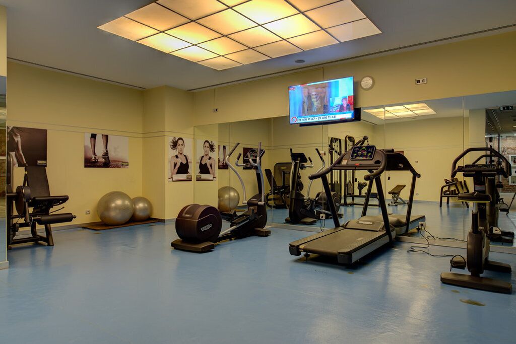 Ein Fitnessraum mit Trainingsgeräten, einem Fernseher und Postern an den Wänden.