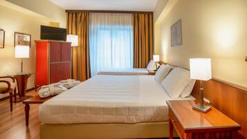A hotel room with a large bed, a desk, a wardrobe, and a television.