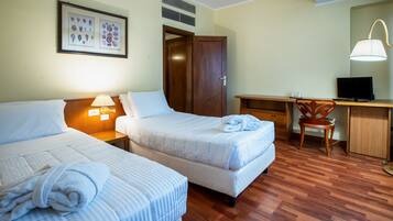 A hotel room with two beds, a desk, a chair, a TV, and a framed picture on the wall.