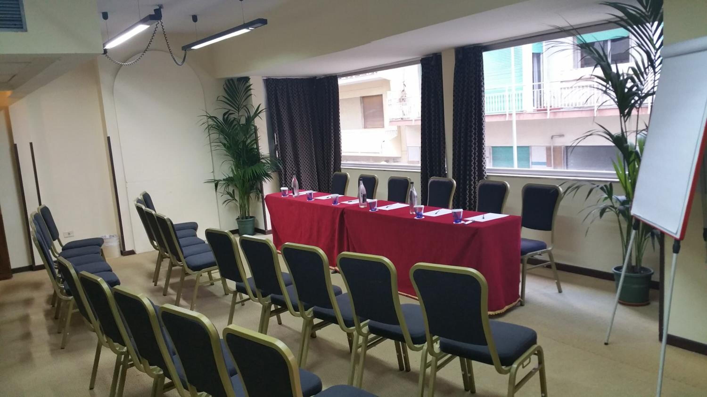 A conference room with a long table, chairs, potted plants, and a whiteboard.
