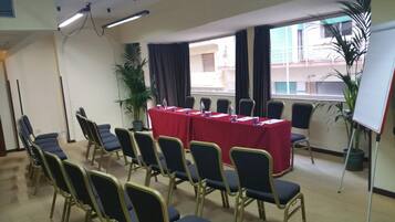 A conference room with a long table, chairs, potted plants, and a whiteboard.