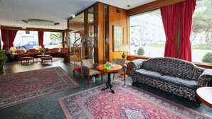 A hotel lobby with a sofa, chairs, a table, and a large rug.