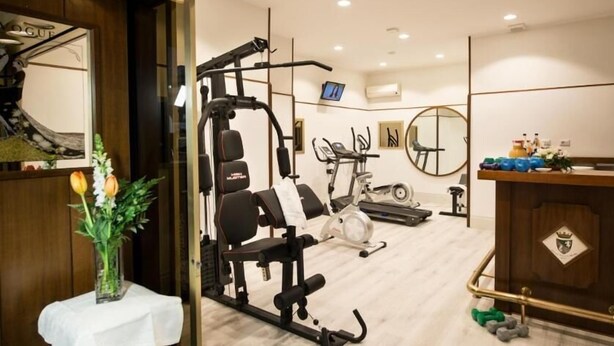 A gym with exercise equipment, a mirror, and a small table with a vase of flowers.