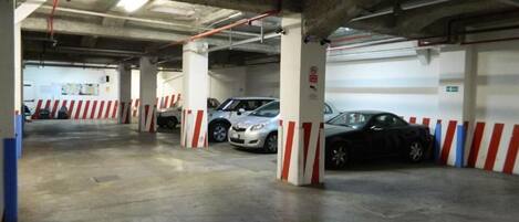 Un estacionamiento subterráneo con pilares de hormigón y barreras delimitadas.