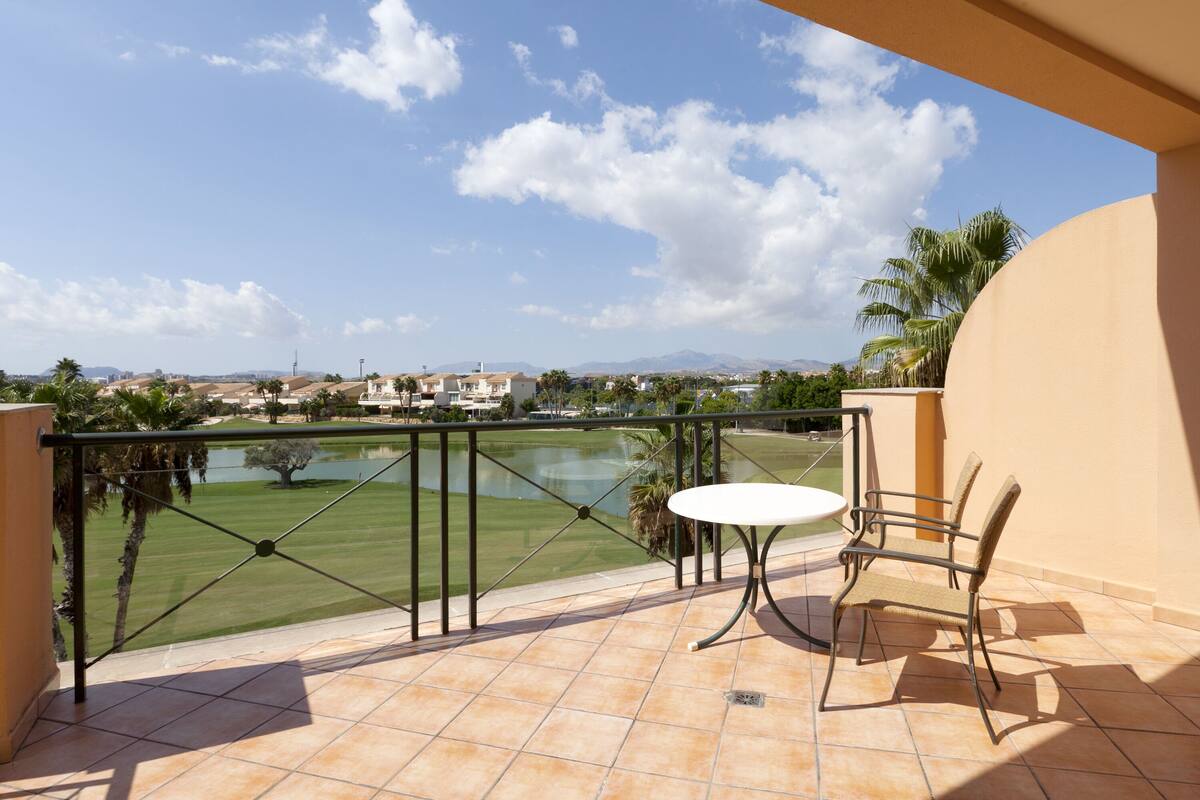 Un balcón con vistas a un campo de golf, una mesa y sillas.