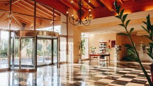 A lobby with a checkered floor, a revolving door, and a chandelier. - Hotel Alicante Golf (Alicante)
