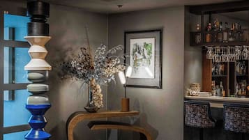 Een modern interieur met een barhoek, een bijzondere wandsculptuur en een ingelijst kunstwerk.