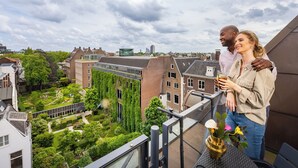 Een balkon met uitzicht op een tuin en gebouwen.