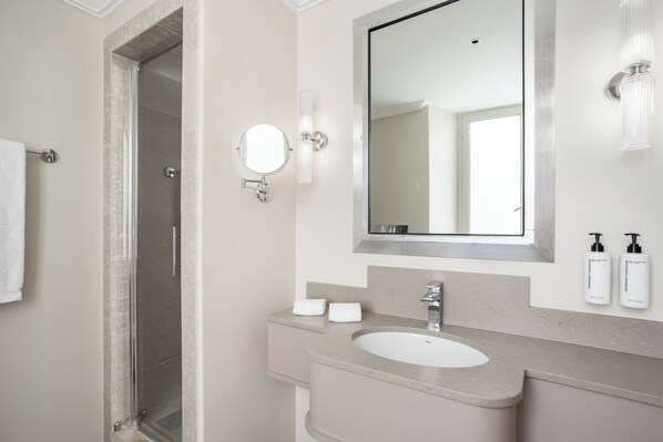 A modern bathroom with a glass shower enclosure, a large mirror, a sink, and toiletries on the countertop. - Room Mate Collection Mia, Rome Colosseum (Rome)