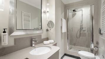 Een moderne badkamer met een grote spiegel, een wastafel, toilet en een douchecabine met glazen wanden.