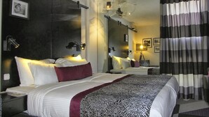 Una habitación de hotel moderna con una cama grande, un espejo y una mesita de noche.