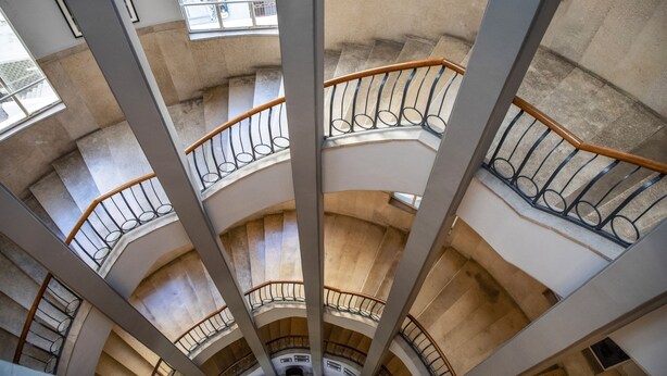 Un interior de varios niveles con una escalera central rodeada de balcones.