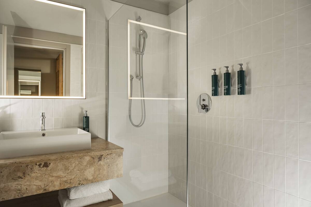 A modern bathroom with a rectangular sink, a glass-enclosed shower, and a mirror.