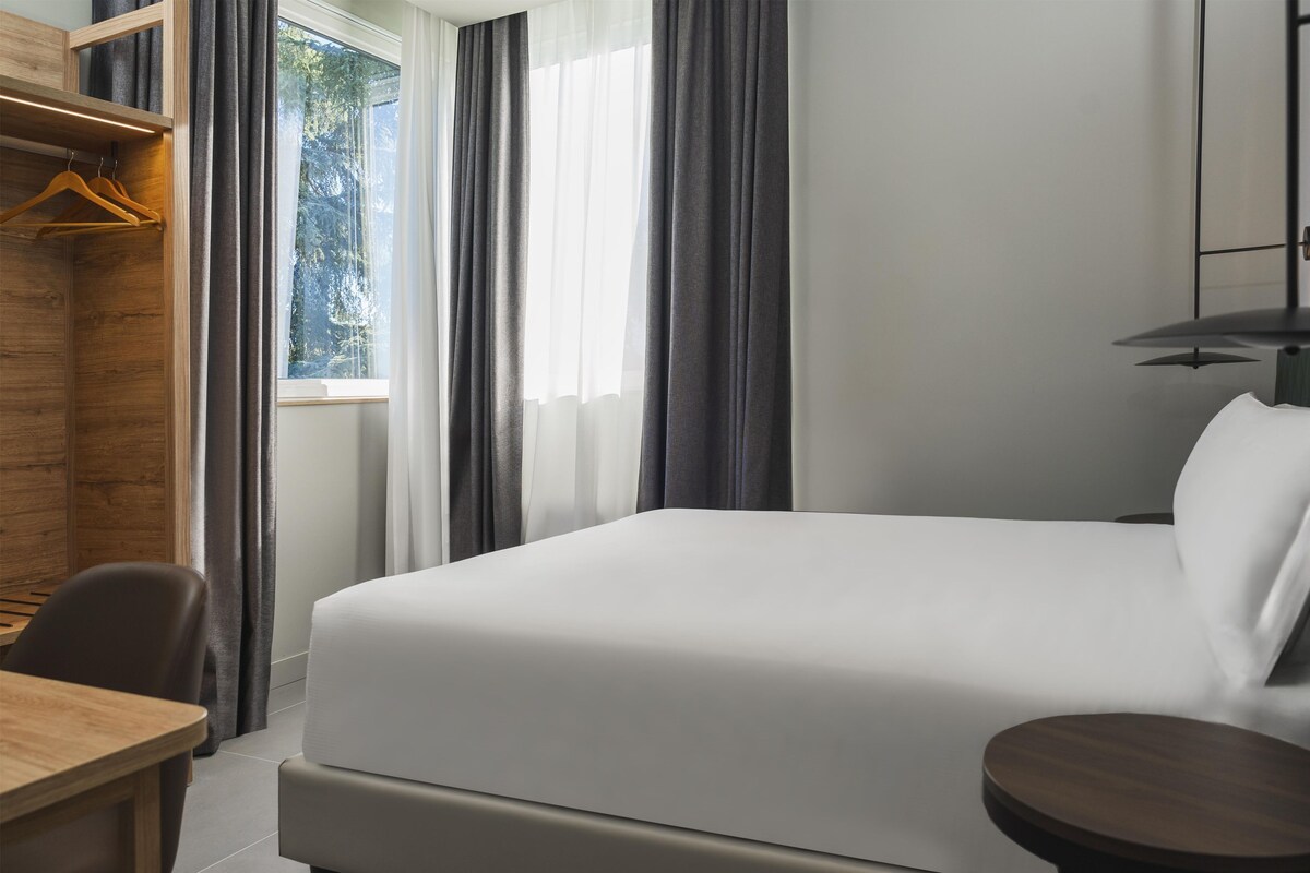 Una camera d'albergo con un letto, una scrivania, una sedia e un tavolino.