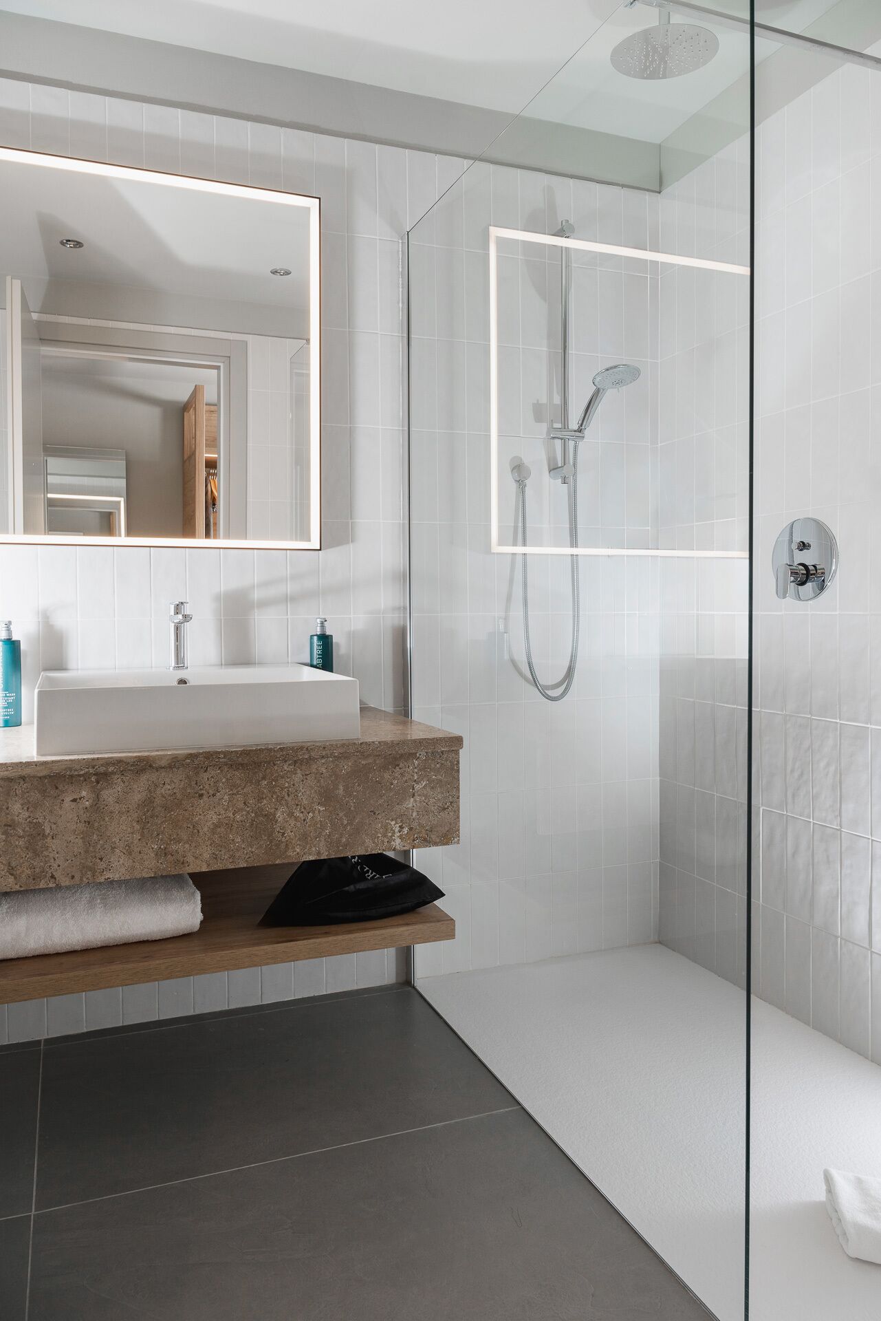A modern bathroom with a glass-enclosed shower, a large mirror, and a marble countertop.