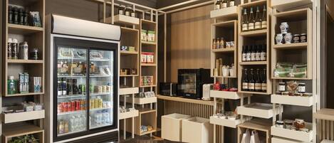 A well-organized retail space with shelves stocked with various products, a refrigerator with beverages, and a coffee machine.