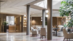 A spacious lobby with a polished marble floor, modern furniture, and a large indoor plant. - Hilton Garden Inn Bologna North (Granarolo dell'Emilia)