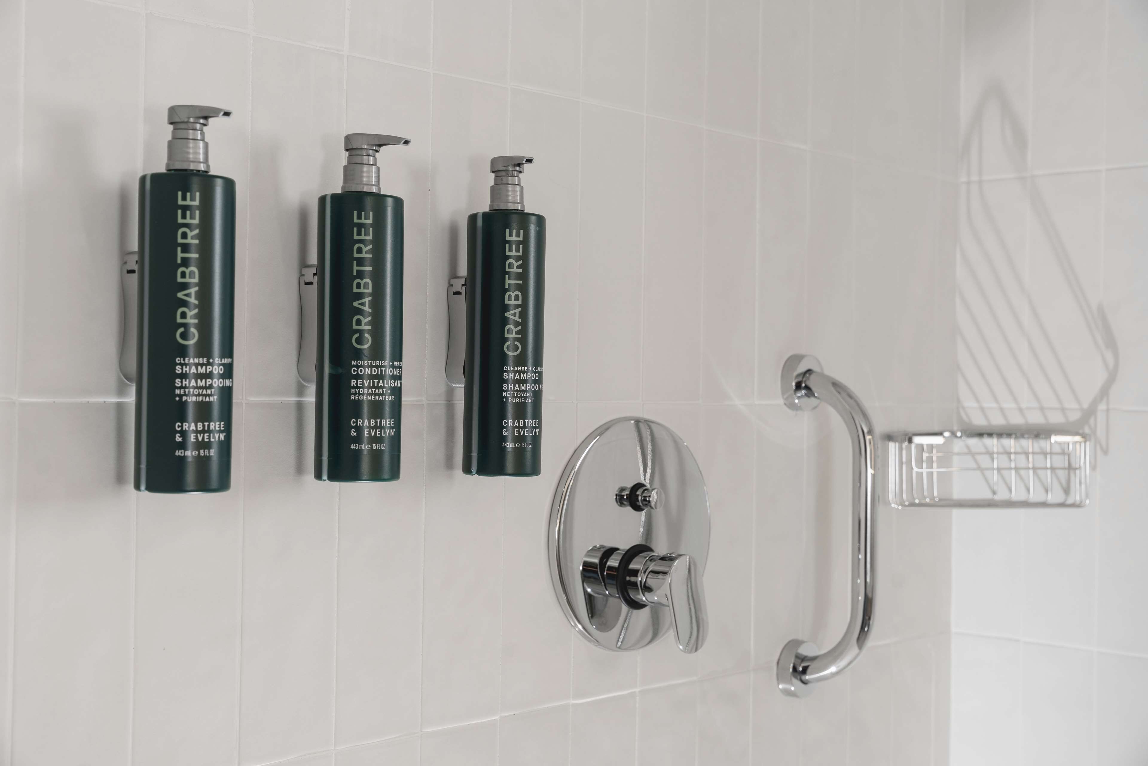 Een badkamer met drie flesjes Crabtree shampoo en een chroom douchekraan.