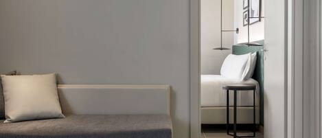A modern, minimalist room with a grey sofa, a small round table, and a white chair.