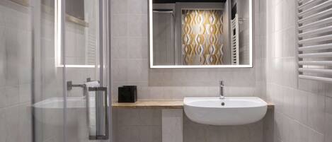 A modern bathroom with a glass shower enclosure, a white sink, and a mirror with a geometric pattern.