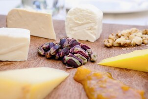 Formaggi e noci assortiti su un tagliere di legno.