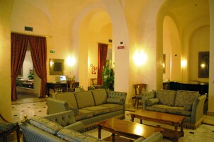 A spacious lobby with a large sofa, smaller seating, a coffee table, and a piano.