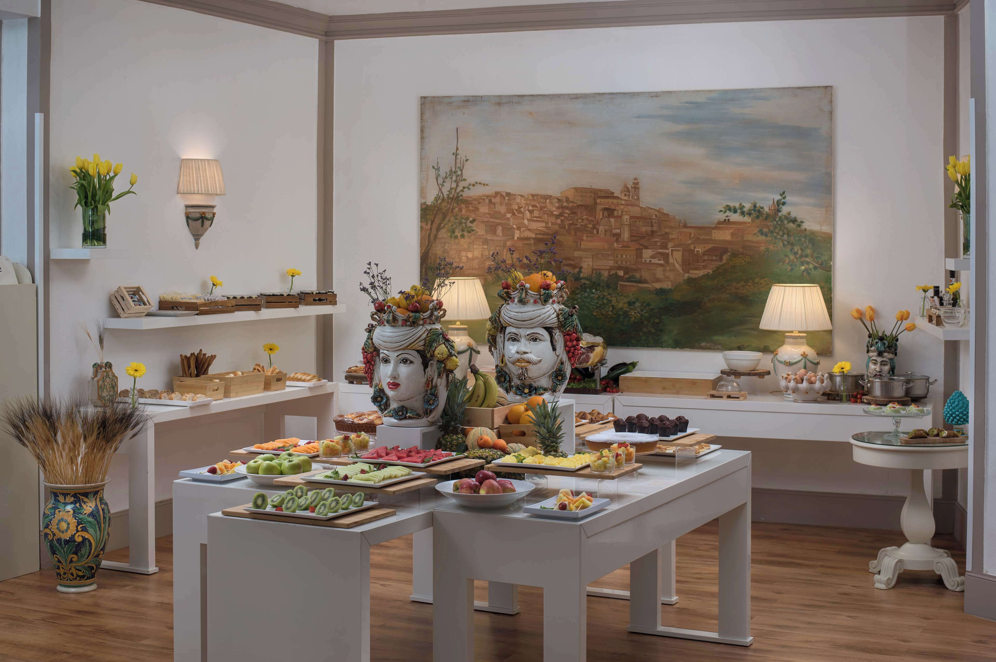 A dining area with a buffet setup, a large painting on the wall, and decorative wall sconces.