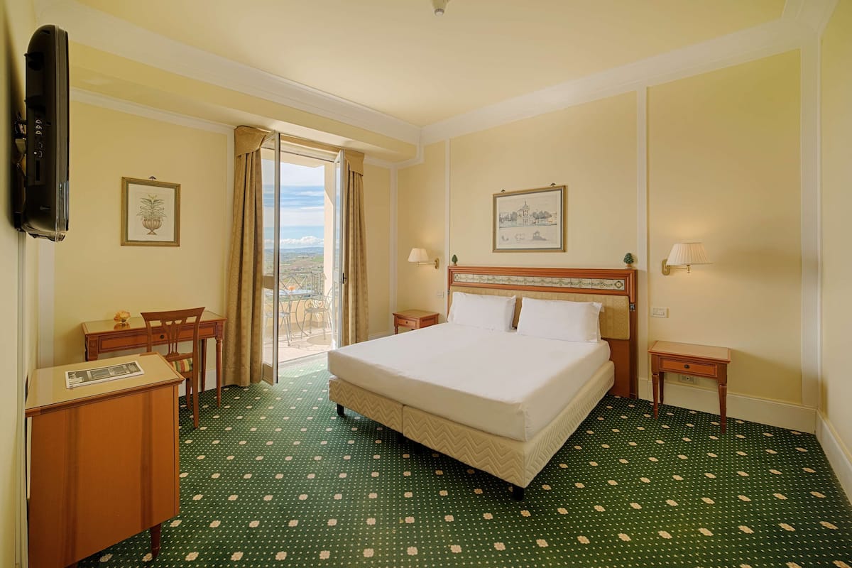 Een hotelkamer met een bed, bureau, stoel, klein tafeltje en een televisie.