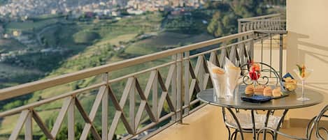 A balcony with a table set for a meal, overlooking a scenic landscape.