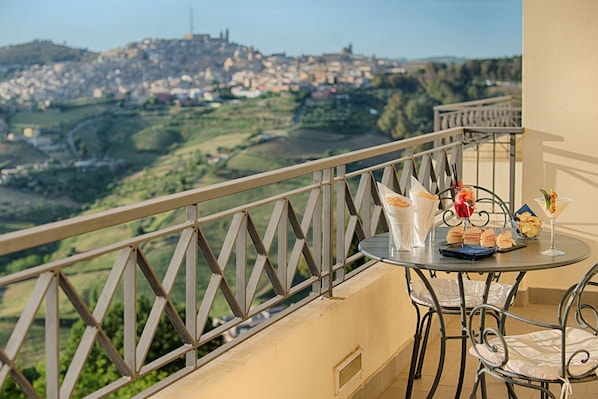 A balcony with a table set for a meal, overlooking a scenic landscape. - NH Caltagirone Villa San Mauro (Caltagirone)