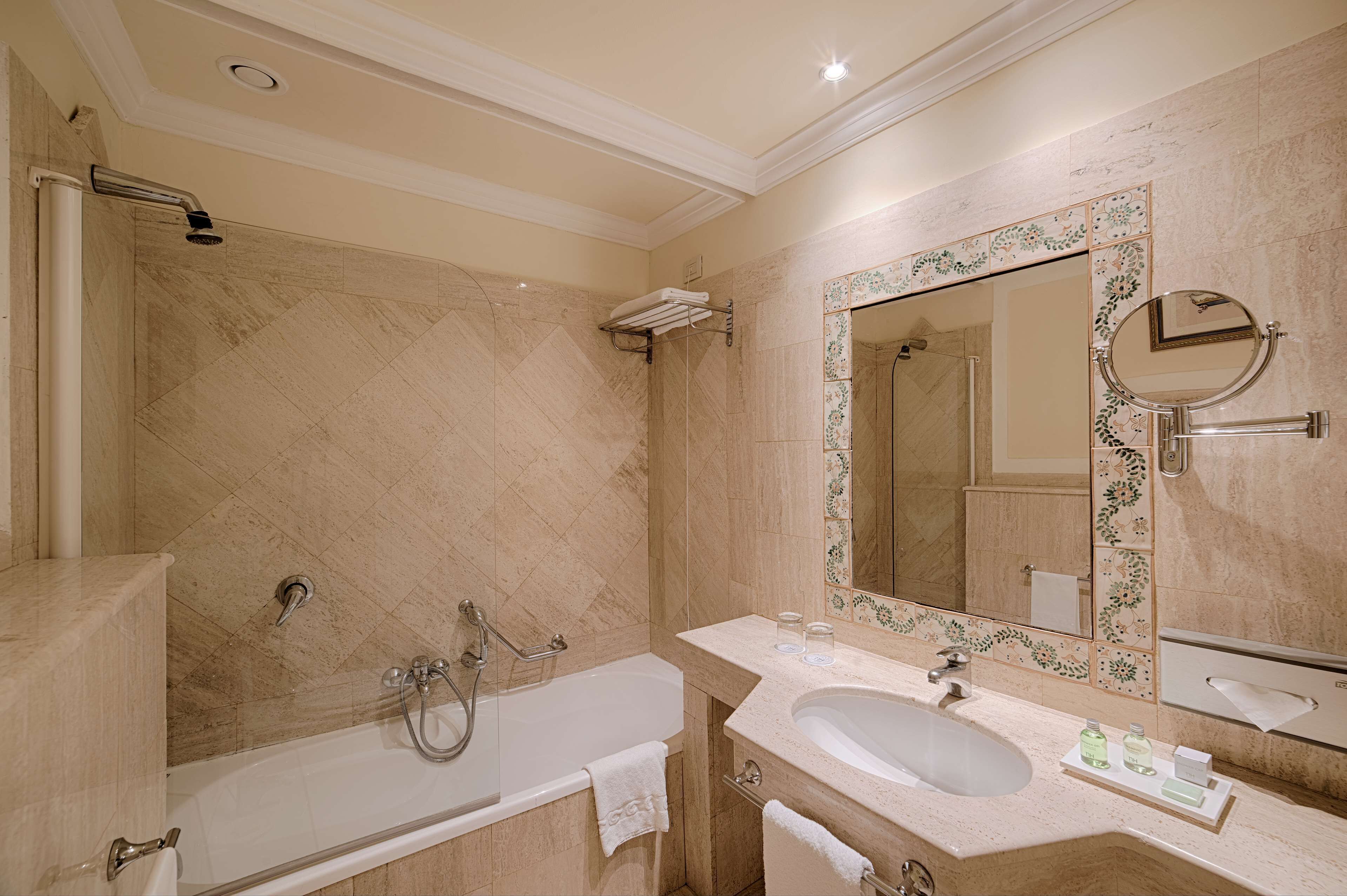 A bathroom with a bathtub, a sink, a shower, and a large mirror.