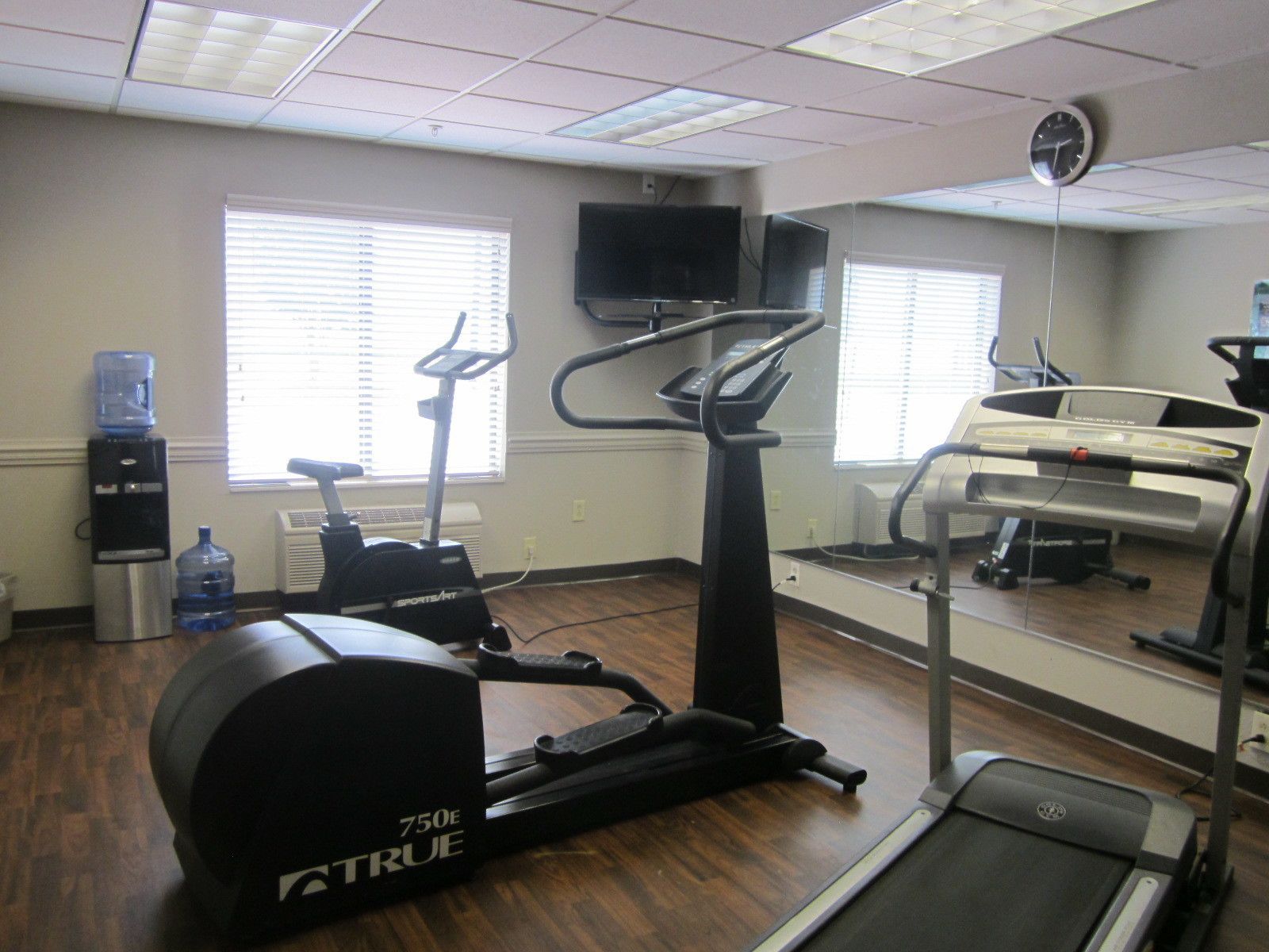 A gym with cardio equipment including a treadmill, elliptical, and stationary bike.